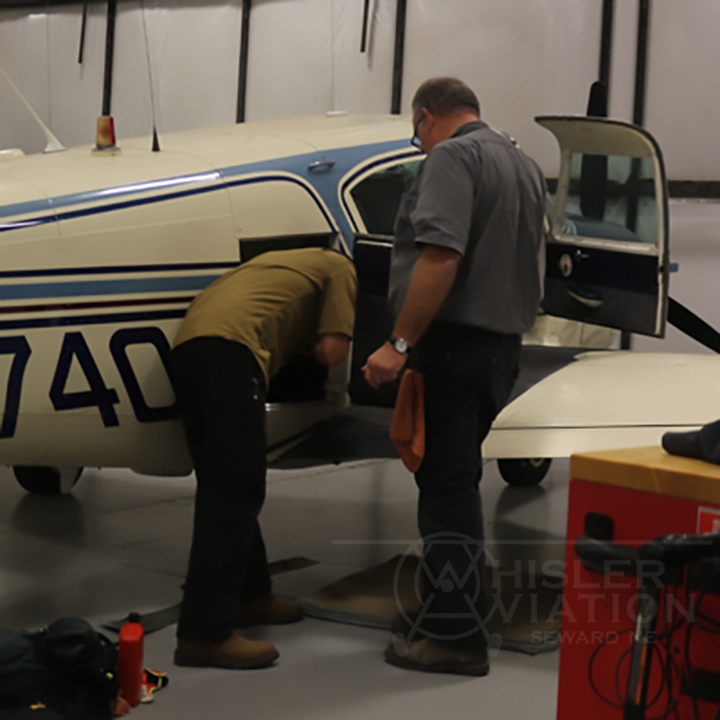 Jon and Greg inspecting compartments of a small aircraft at Whisler Aviation in Seward Nebraska