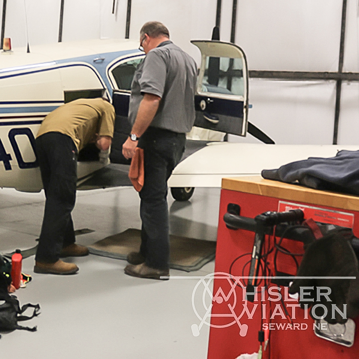 Jon and Greg inspecting compartments of a small aircraft at Whisler Aviation in Seward Nebraska