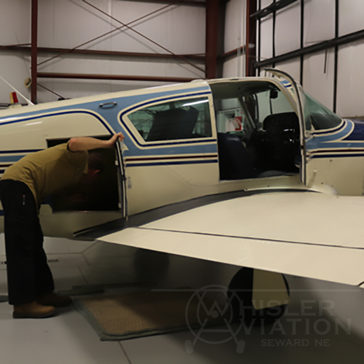 Jon inspecting compartments of a small aircraft at Whisler Aviation in Seward Nebraska